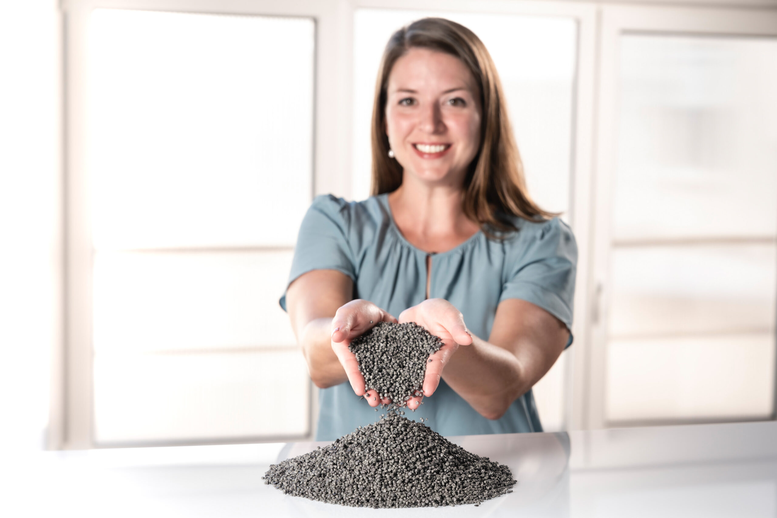 Mujer interactúa con pellets de aditivos para plásticos.